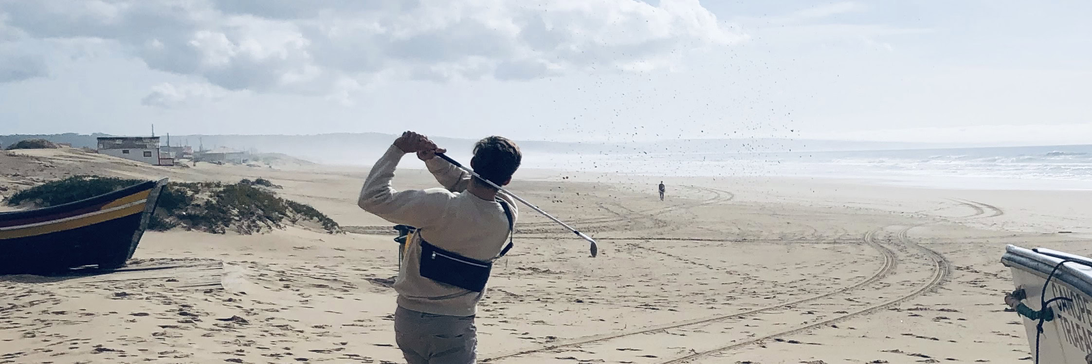 A nonchalant golf player teeing off on the beach casually wearing a Manufabo Belt Bag